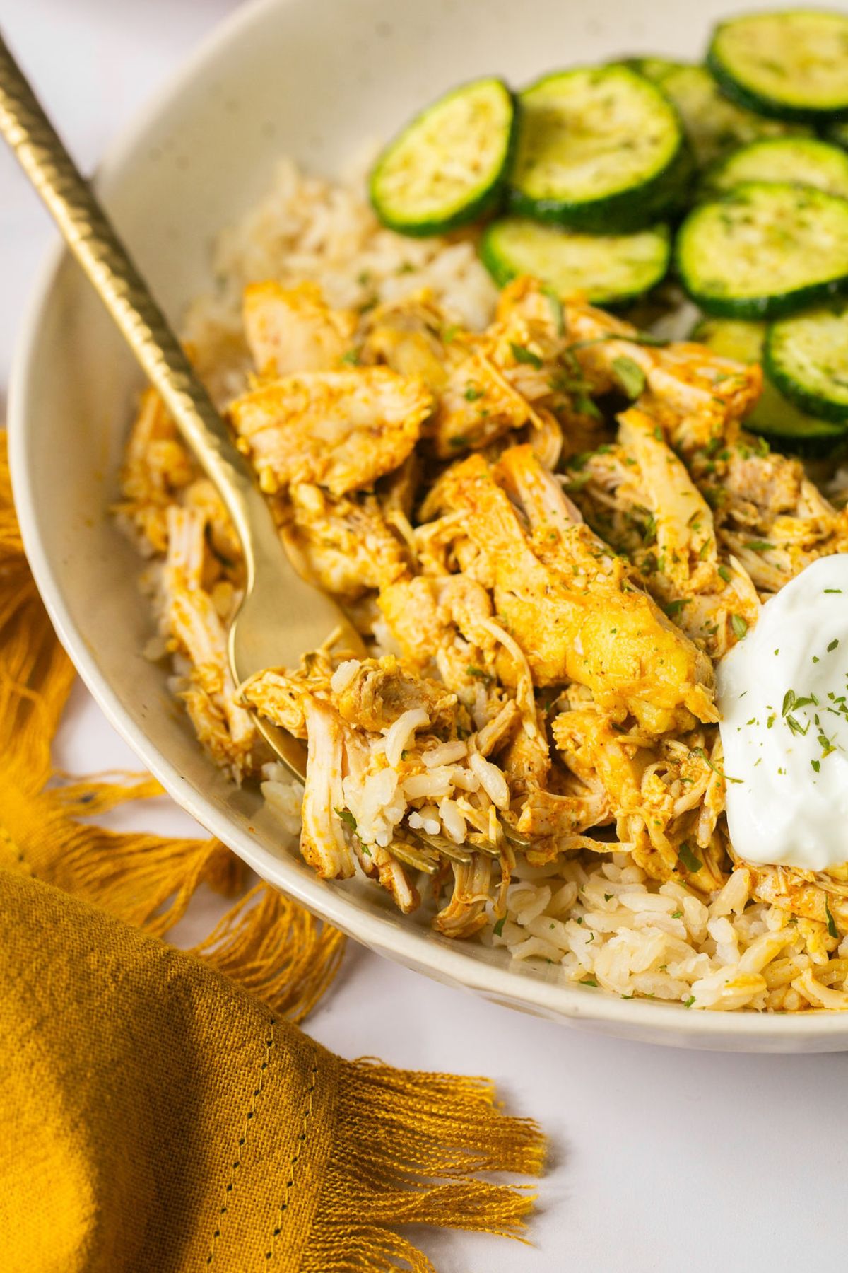 Crock pot chicken shawarma in a bowl with rice and sliced zucchini.