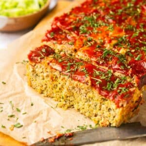 Gluten-free meatloaf made with zucchini and carrots on a cutting board cut into slices.