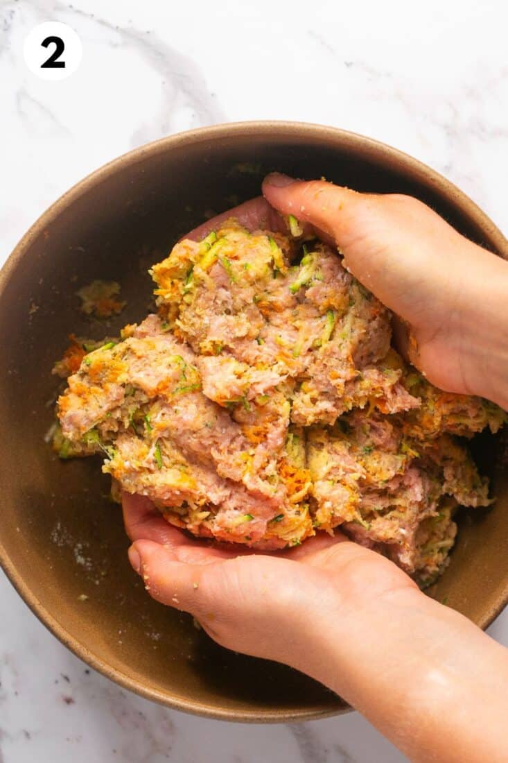 Hands mixing the paleo meatloaf ingredients together.