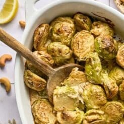 Brussels sprouts casserole on the table with a wooden spoon scooping some up.