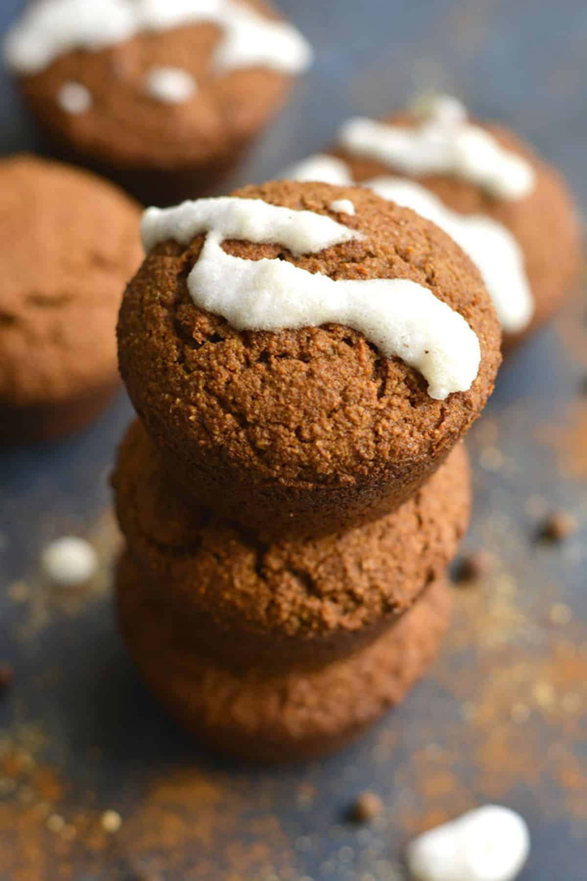 A stack of three gingerbread muffins with some white icing on the one on top.