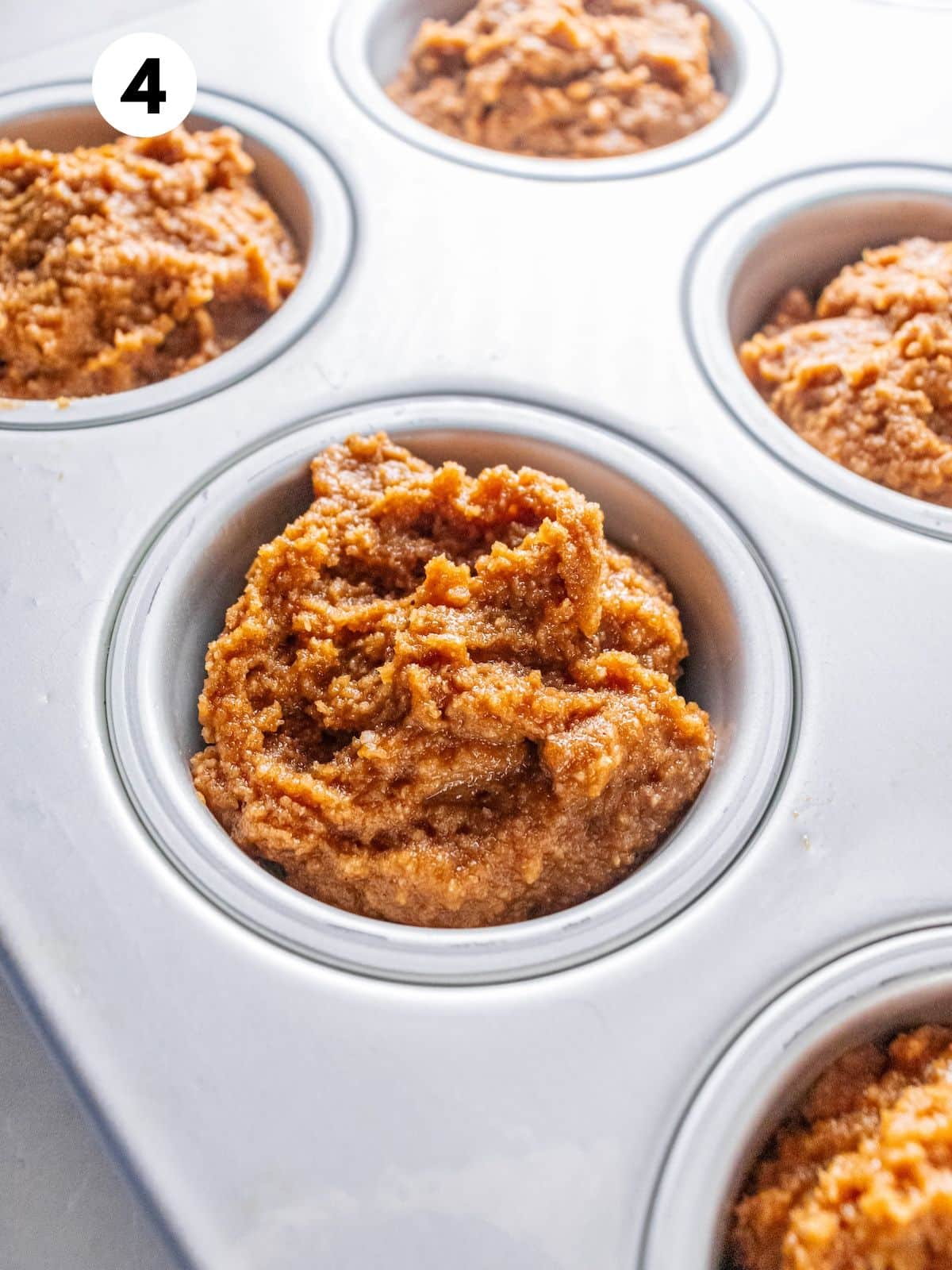 Gingerbread muffin batter added to a muffin pan.