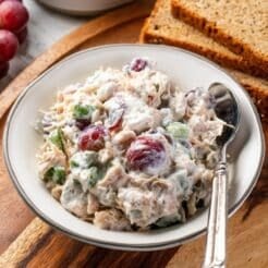 A bowl of healthy chicken salad on the table with a spoon on the side.