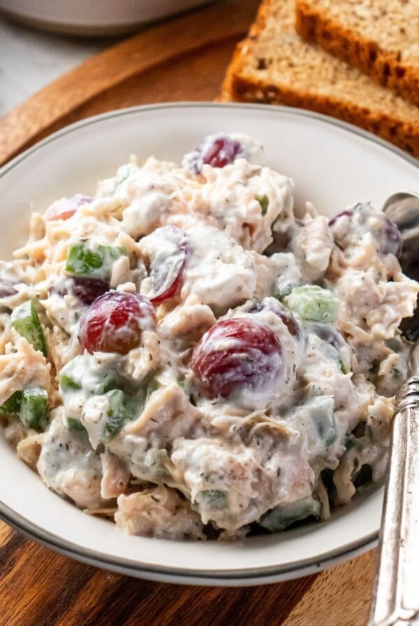 A bowl of healthy chicken salad on the table with a spoon on the side.