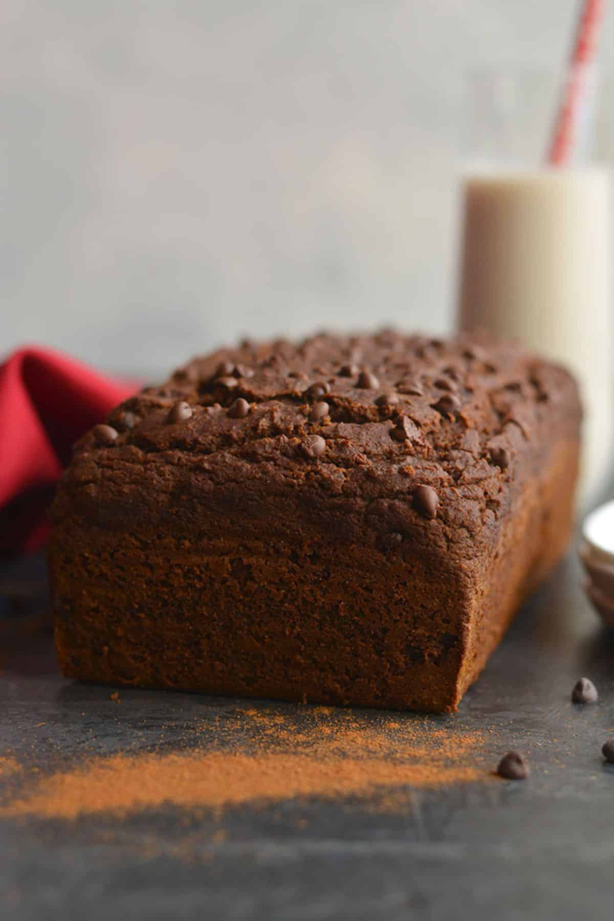 Baked chocolate gingerbread cake with some cocoa powder dusted on the counter in front.
