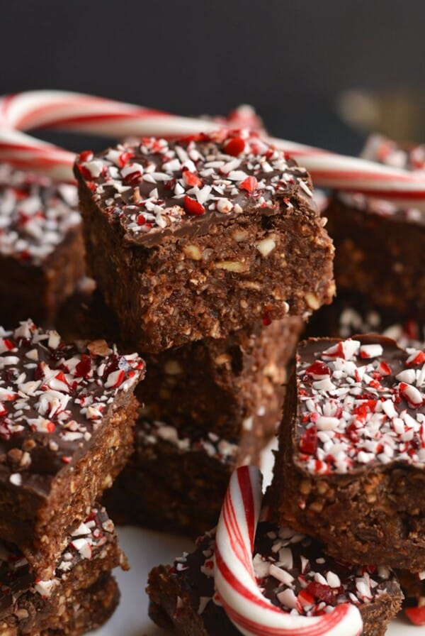 A stack of. no bake peppermint brownies with candy canes on a table.