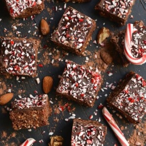 Peppermint brownies piled up on different angles with candy canes scatttered.
