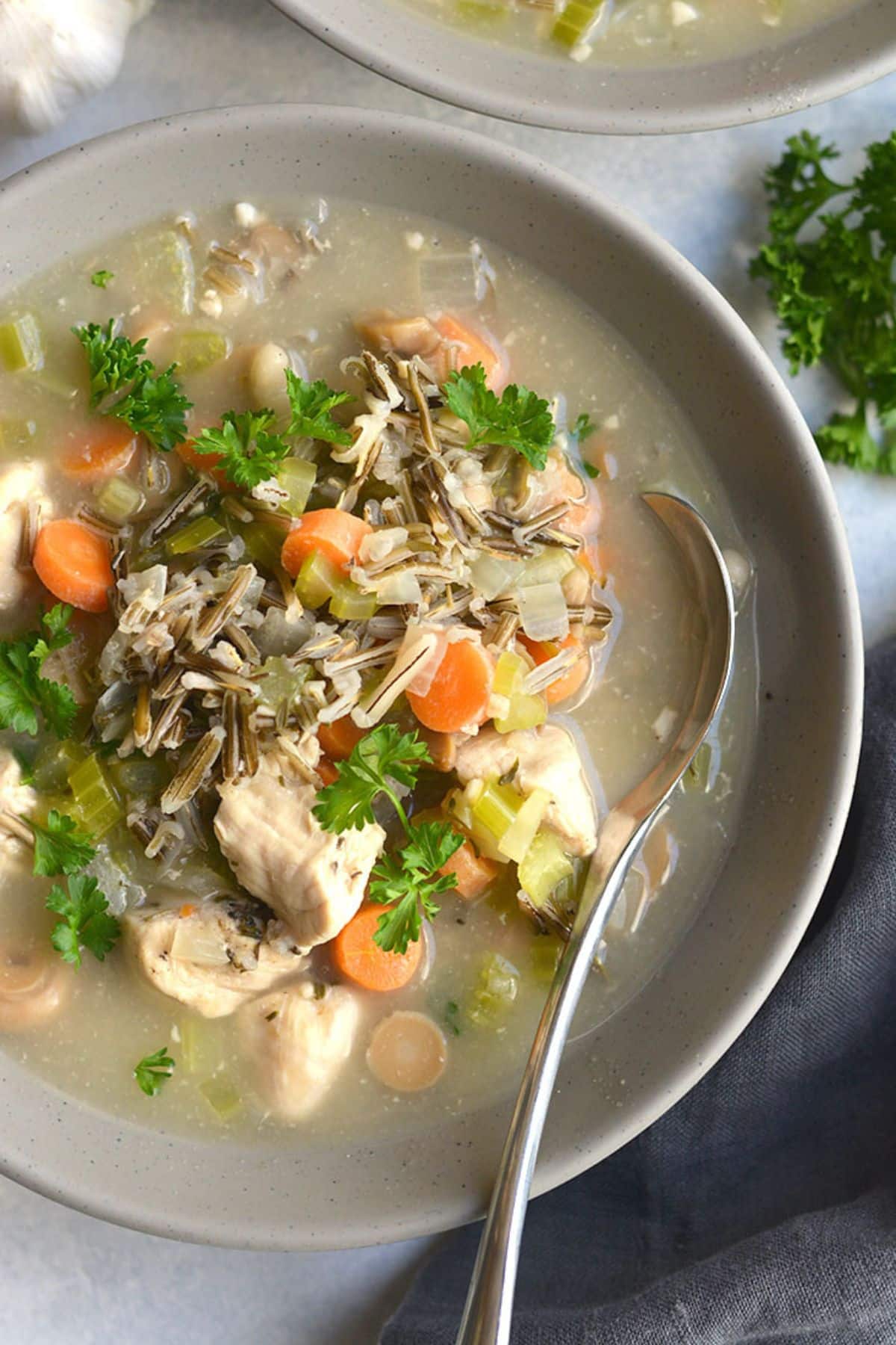 A pot of chicken wild rice soup with a spoon resting in it to the side.