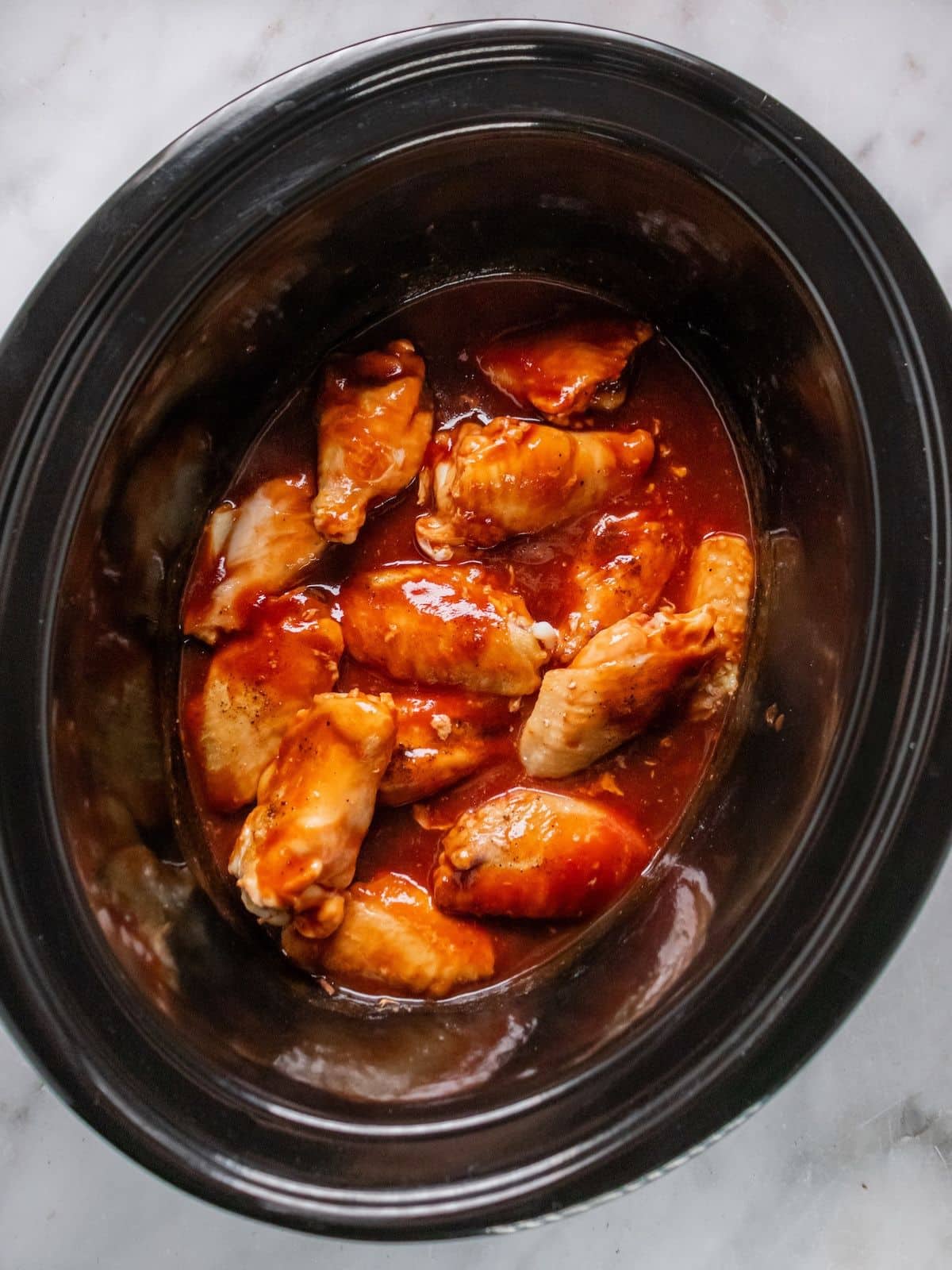 Chicken wings added to the bbq sauce in the slow cooker.