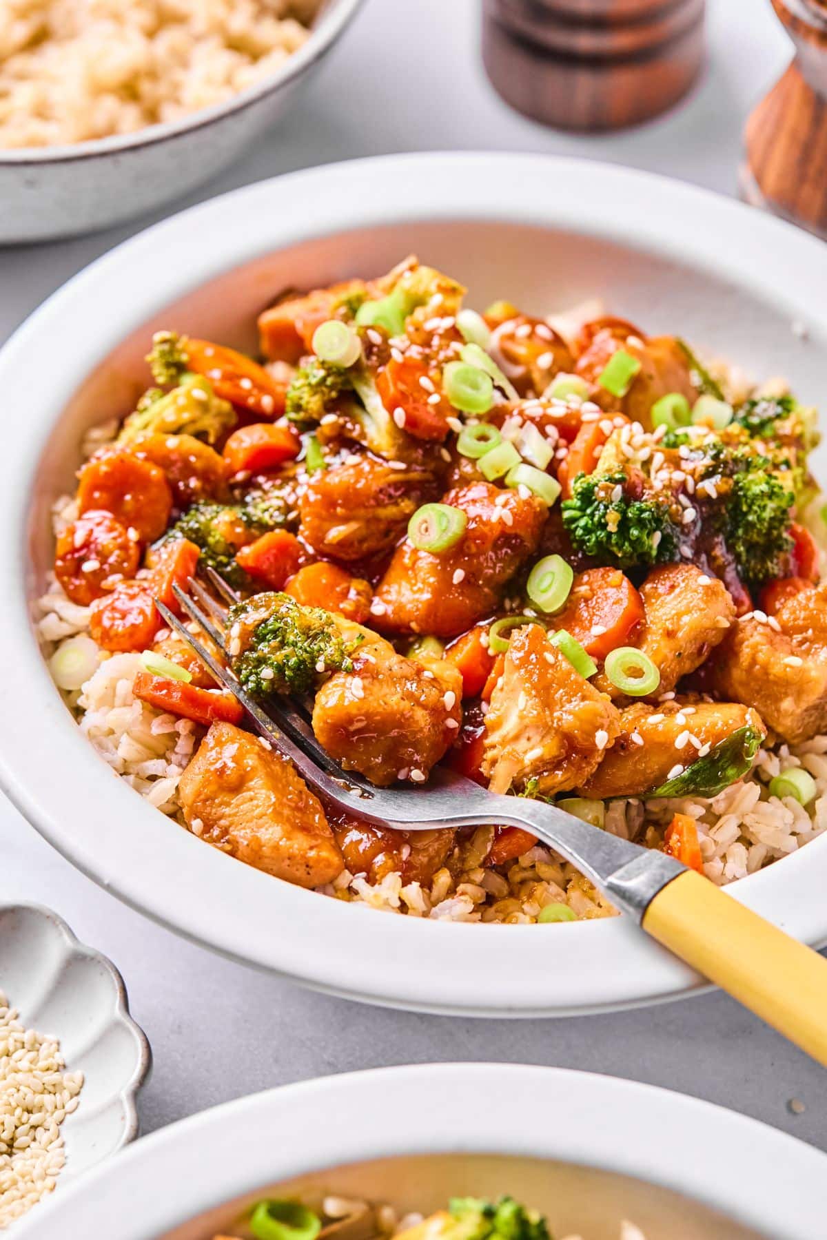 A bowl full of mongolian chicken with a fork resting in the bowl.