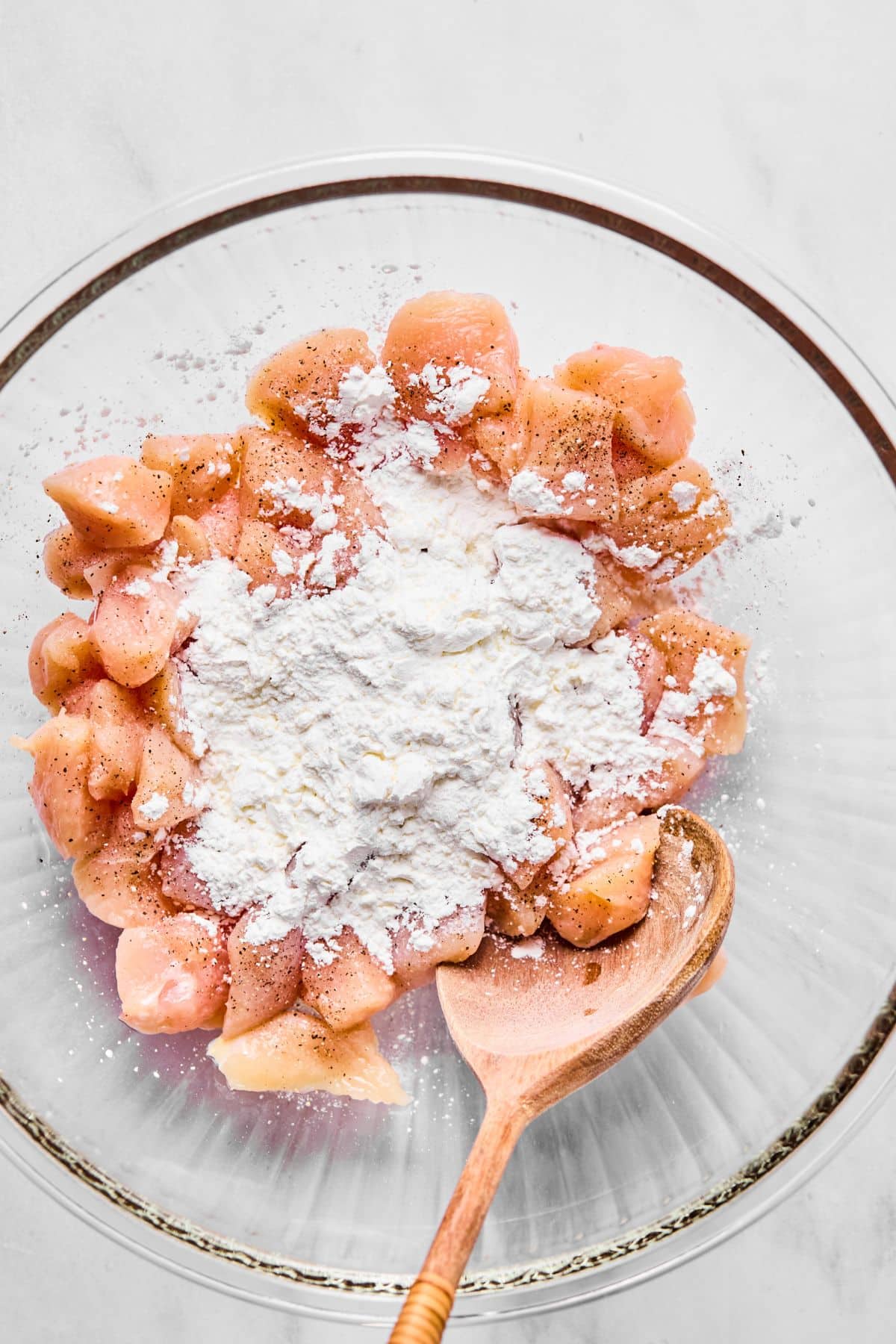 Chicken cubes and cornstarch in a mixing bowl.