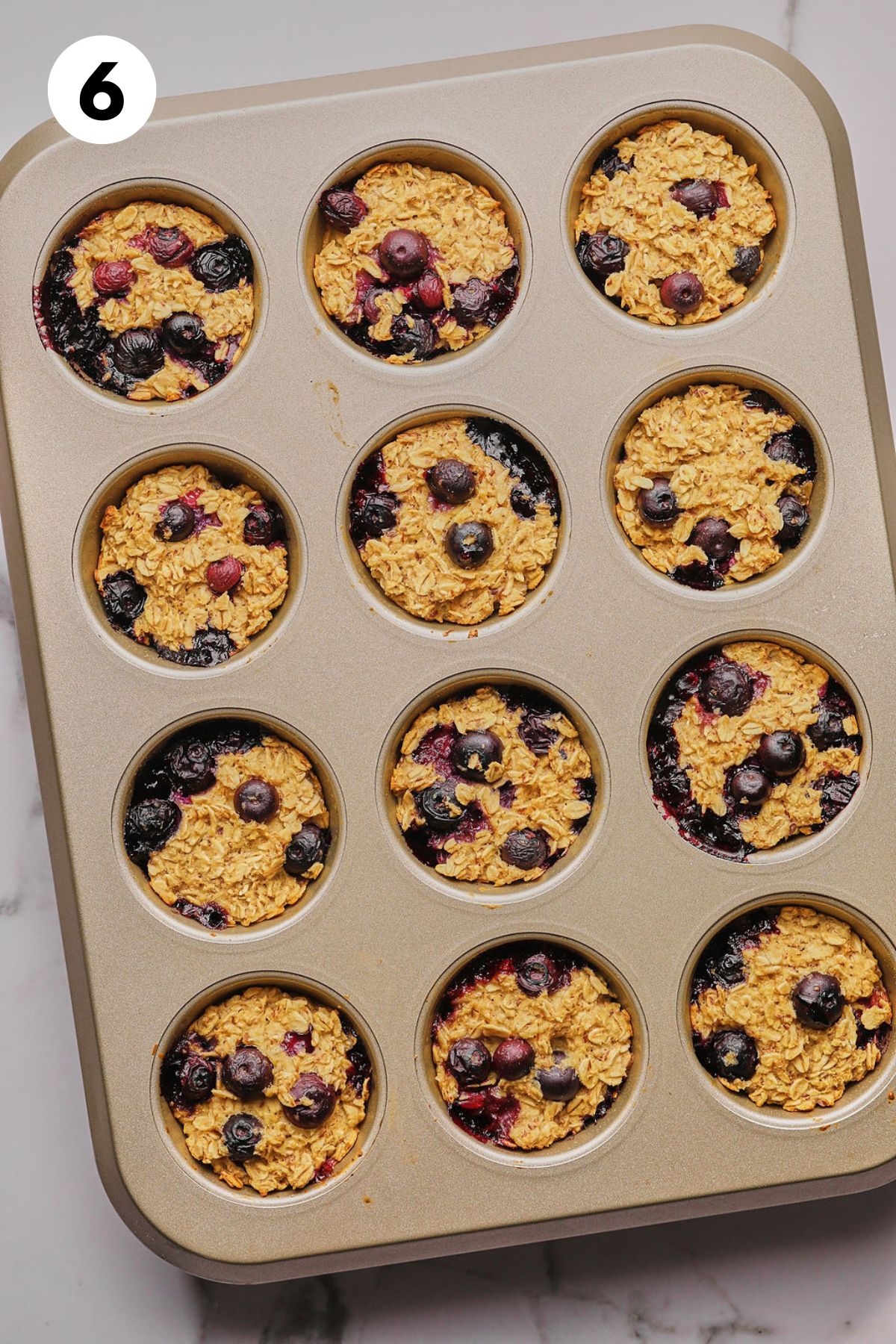 Blueberry muffin batter in a muffin tin.