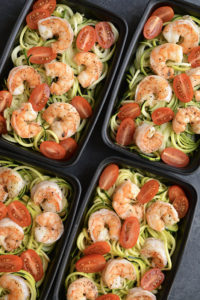 Meal Prep Shrimp Zucchini Noodles! Zesty lemon garlic shrimp is topped over zucchini noodles with sliced tomatoes. Baked on a sheet pan in under 10 minutes! A light, fresh and satisfying low carb meal to take with you on the go! Paleo + Gluten Free + Low Calorie