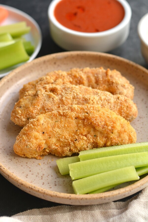 Almond Flour Buffalo Chicken Tenders! These better for you chicken tenders are made with healthy fat and protein from almond flour instead of traditional breadcrumbs that are higher in carbohydrates. This lighter meal is quick to make in under 30 minutes and healthier. Paleo + Gluten Free + Low Calorie