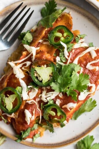 A serving of high protein enchiladas on a plate with a fork.