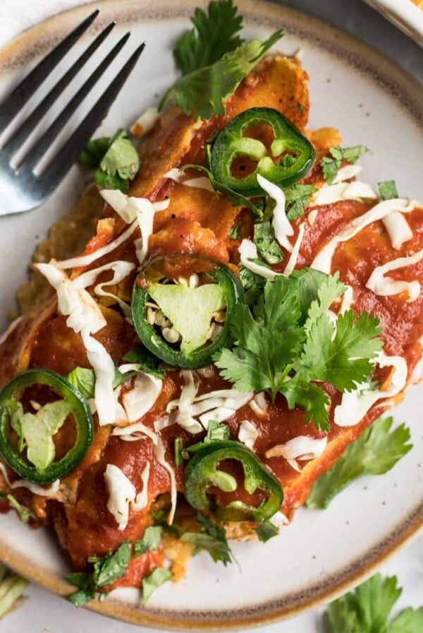 A serving of high protein enchiladas on a plate with a fork.