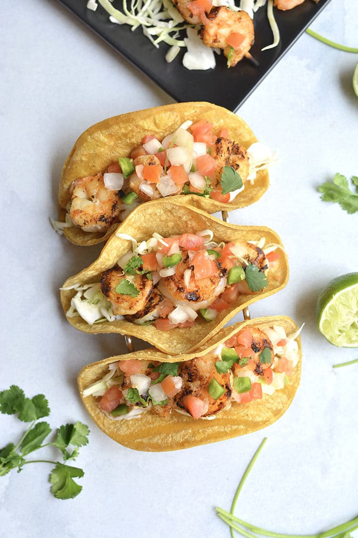 10 Minute Grilled Shrimp Tacos! This lightened up recipe shows you how to do tacos healthier and in a breeze. Grilling shrimp produces delicious flavor and can be easily done with a grill pan. A healthy dinner for busy weeknights or weekend BBQ's! Gluten Free + Low Calorie with a Paleo option
