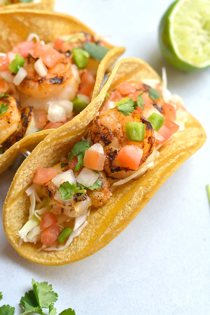 10 Minute Grilled Shrimp Tacos! This lightened up recipe shows you how to do tacos healthier and in a breeze. Grilling shrimp produces delicious flavor and can be easily done with a grill pan. A healthy dinner for busy weeknights or weekend BBQ's! Gluten Free + Low Calorie with a Paleo option