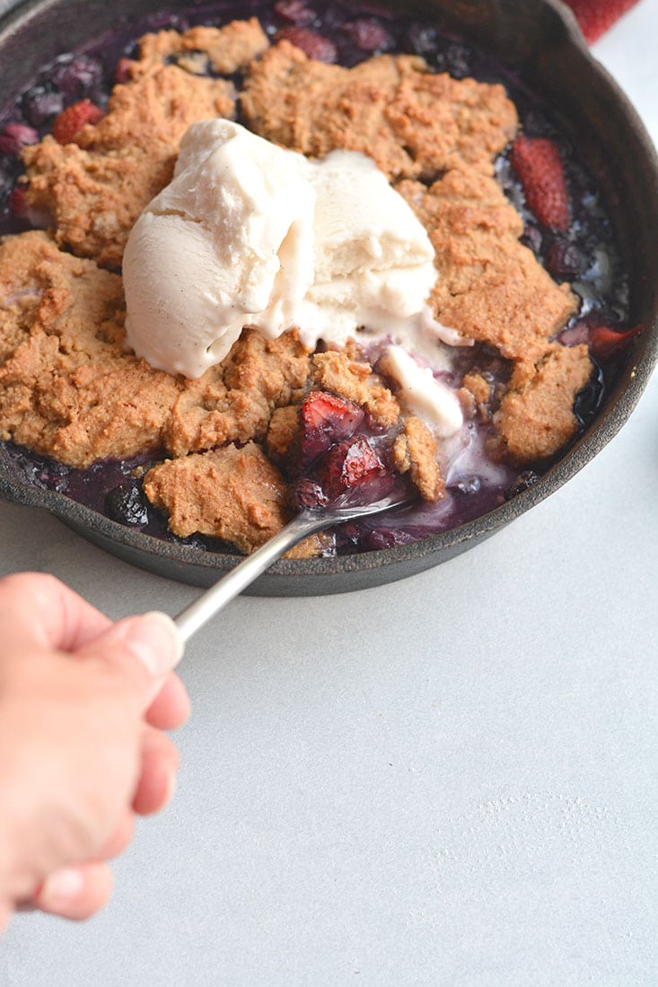 Low Sugar Berry Cobbler is the ultimate summertime treat! Made in one skillet with glycemic friendly ingredients. Low in calories and higher in protein than traditional cobblers, this warm weather dessert is sure to be your new favorite treat. Paleo + Gluten Free Options