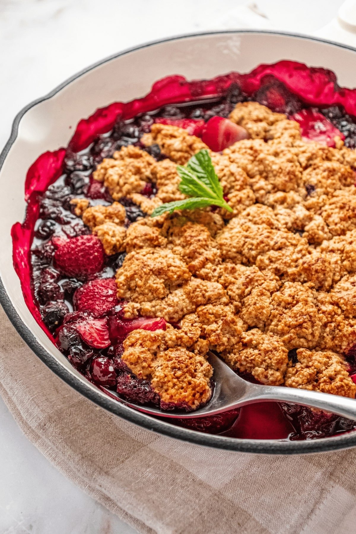 A gluten-free berry cobbler with a spoon resting in the dish.