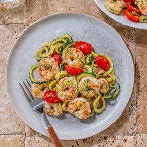 Shrimp pesto on a white plate with a fork resting to the side.