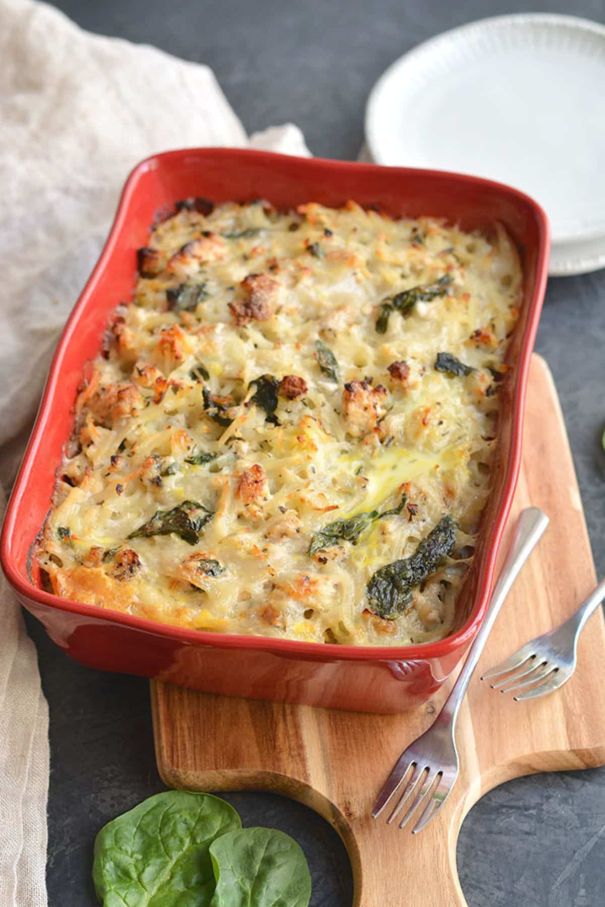 A casserole with chicken, potatoes, egg and spinach in a dish.