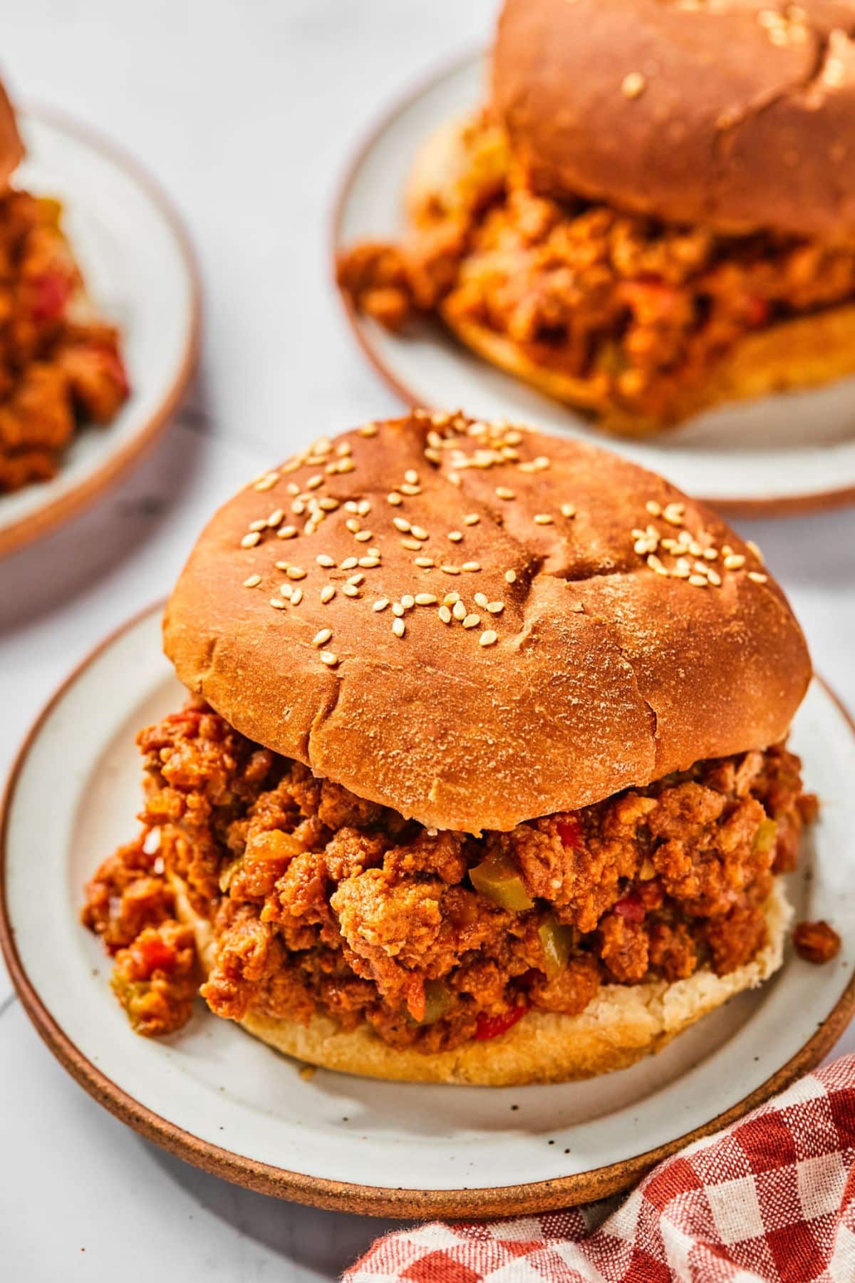 Turkey sloppy joes on plates on the table served up on buns.