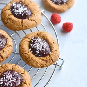 Paleo Raspberry Coconut Thumbprint Cookies! No one will guess these easy to bake coconut and nut butter cookies made with raspberry chia jam are grain free!