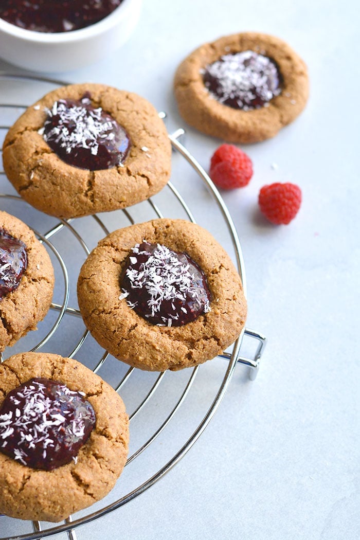 Paleo Raspberry Coconut Thumbprint Cookies! No one will guess these easy to bake coconut and nut butter cookies made with raspberry chia jam are grain free! 