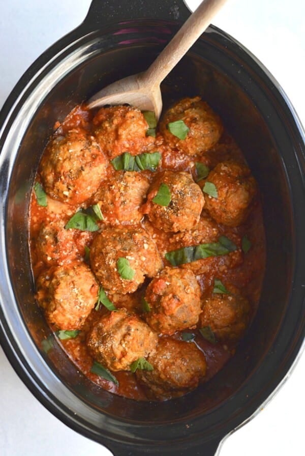 Crockpot turkey meatballs in the slow cooker with a wooden spoon.