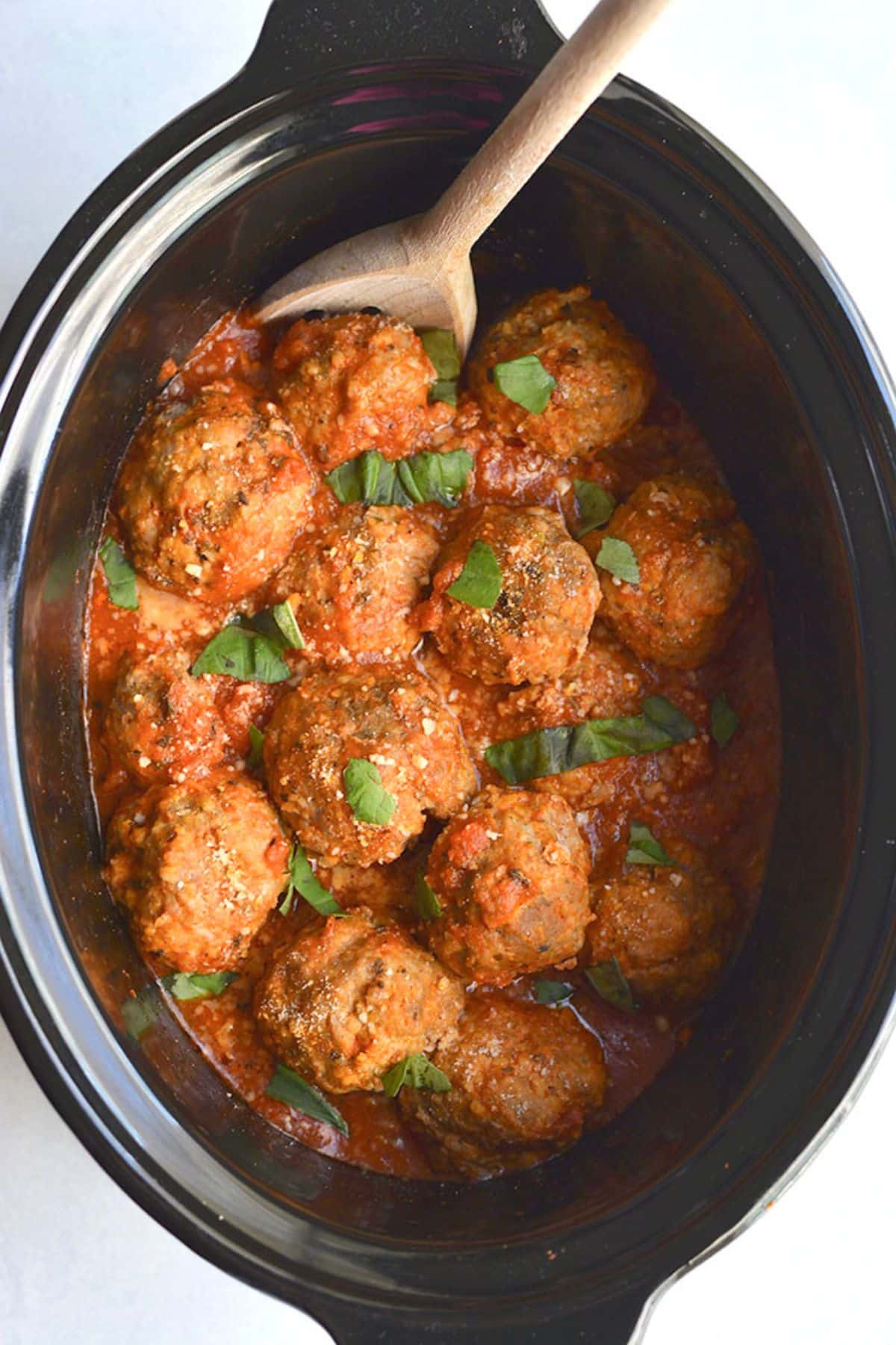 Crockpot turkey meatballs in the slow cooker with a wooden spoon.