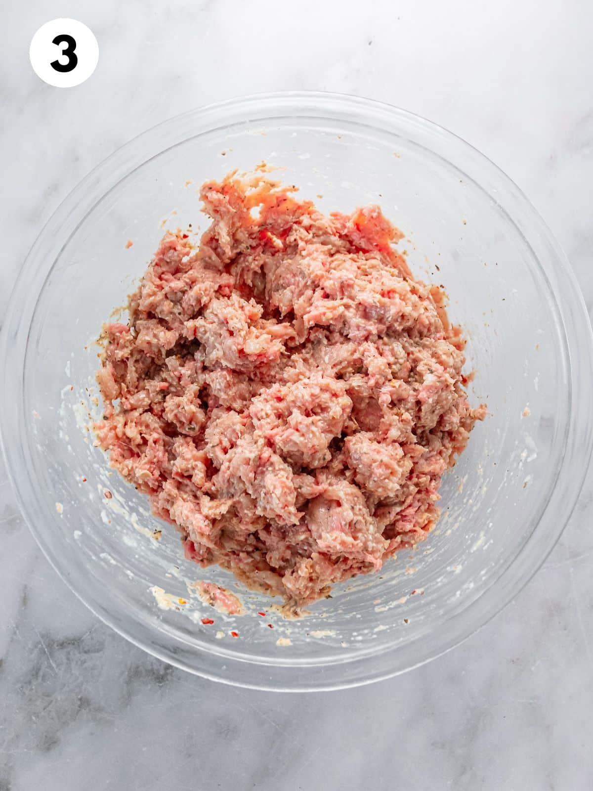 Meat and seasonings combined in a bowl to make turkey meatballs.