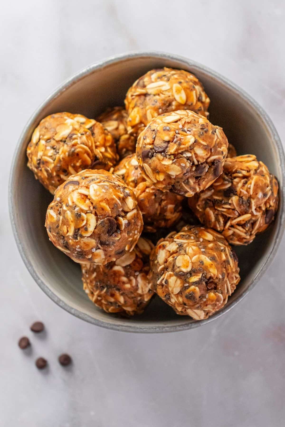 A bowl of almond butter protein balls with some chocolate chips to the side.