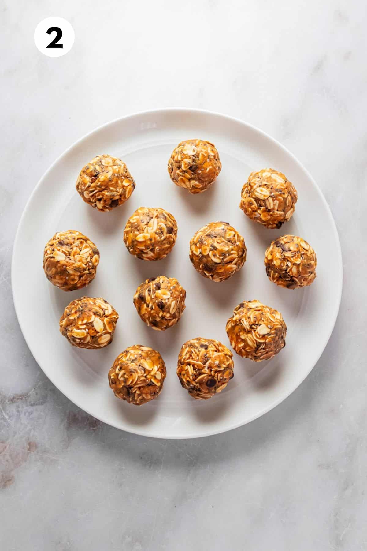 Almond butter energy balls rolled out on a white plate.