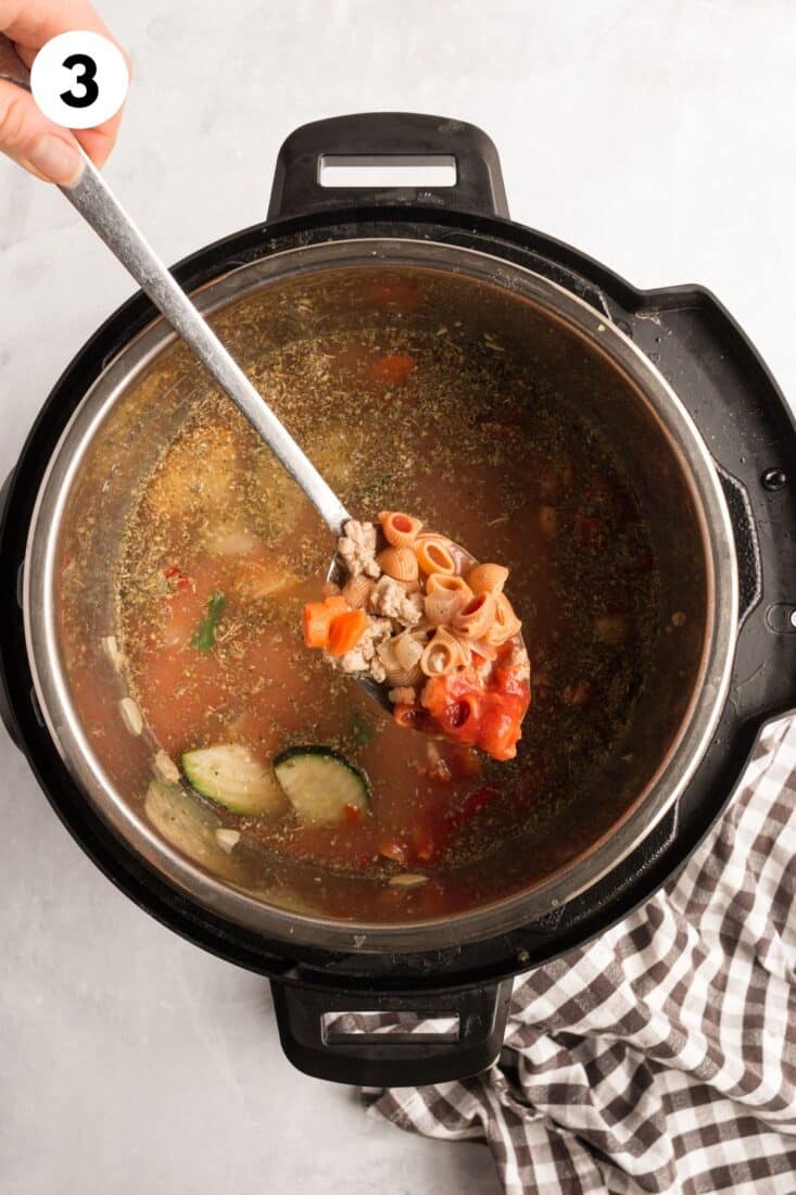 Cooked high protein soup in the instant pot with a spoon lifting some up above the pot.