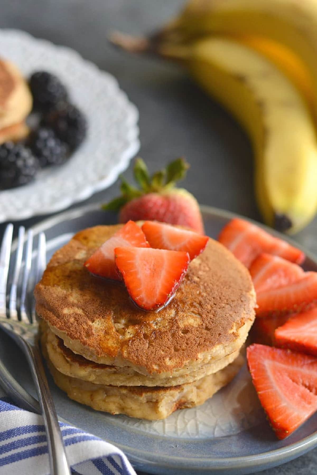 pancakes on a blue plate with sliced strawberries.