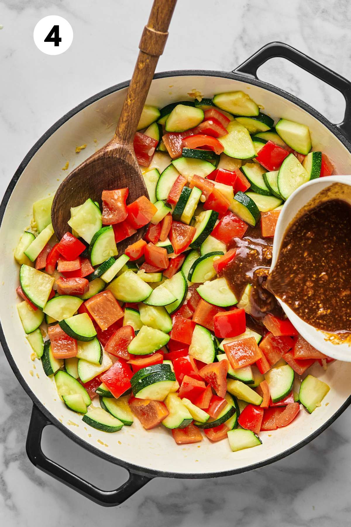 Adding the sauce to the skillet of vegetables.