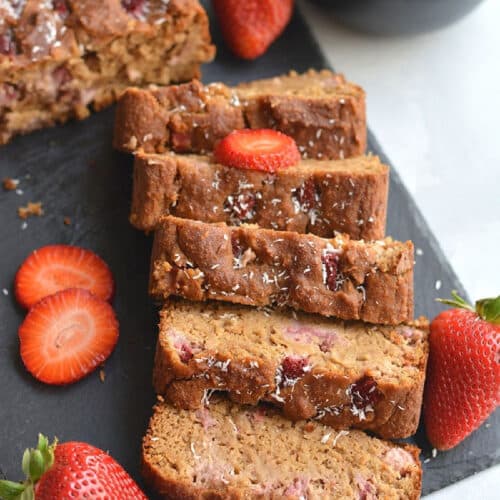 sliced bread on a black tray with sliced strawberries.