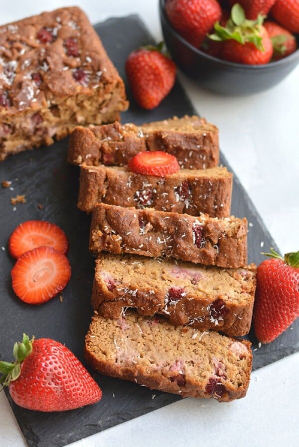sliced bread on a black tray with sliced strawberries.