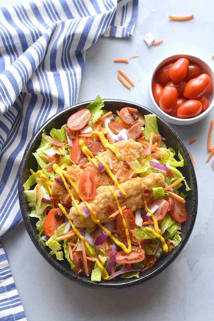 Paleo Honey Mustard Chicken Salad! Crispy almond flour tenders served over a bacon salad with a lightened up honey mustard dressing. A healthier mustard chicken that's family approved! Gluten Free + Paleo + Low Calorie