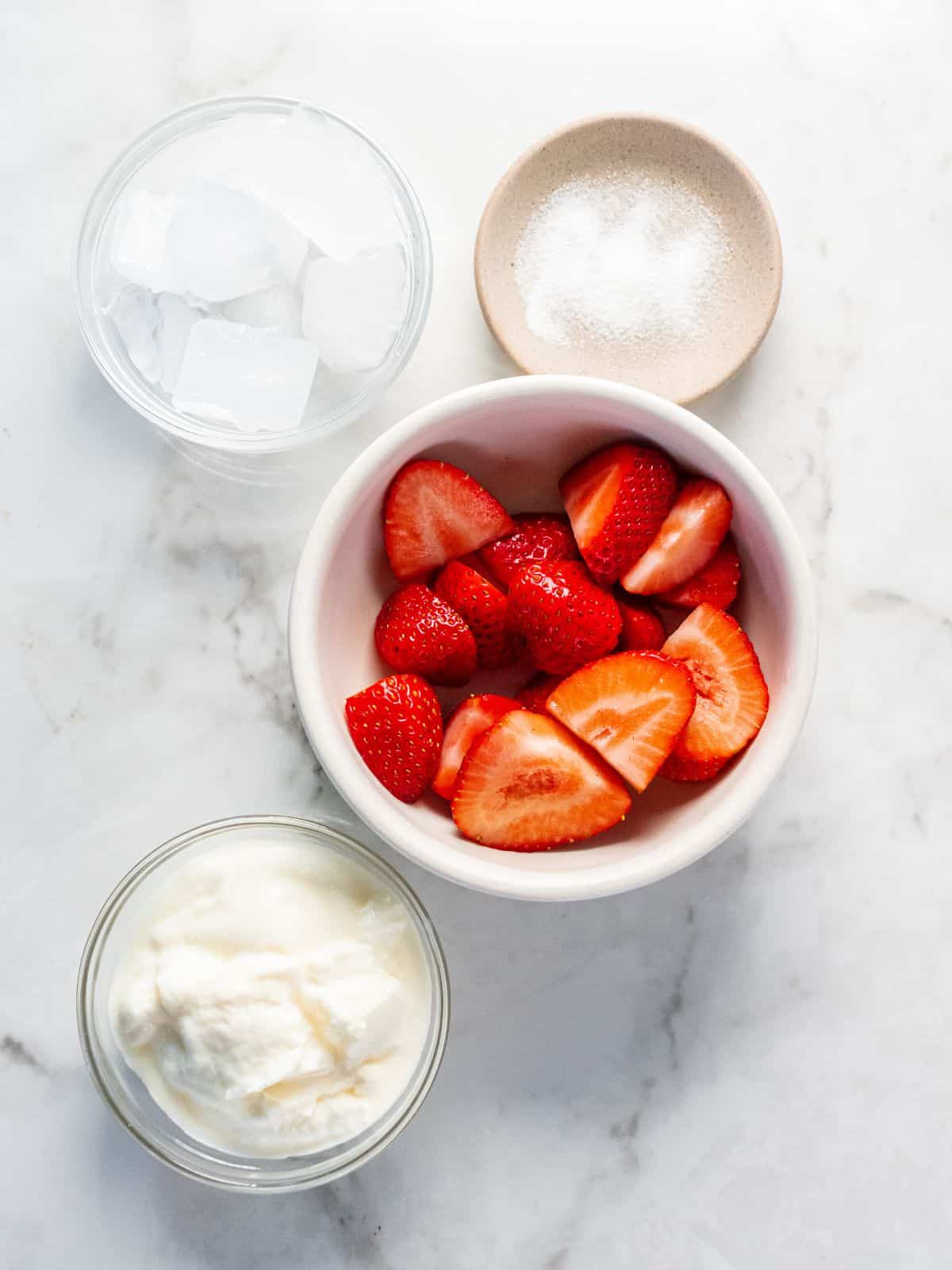 Ingredients to make greek yogurt smoothies with strawberries on the table.