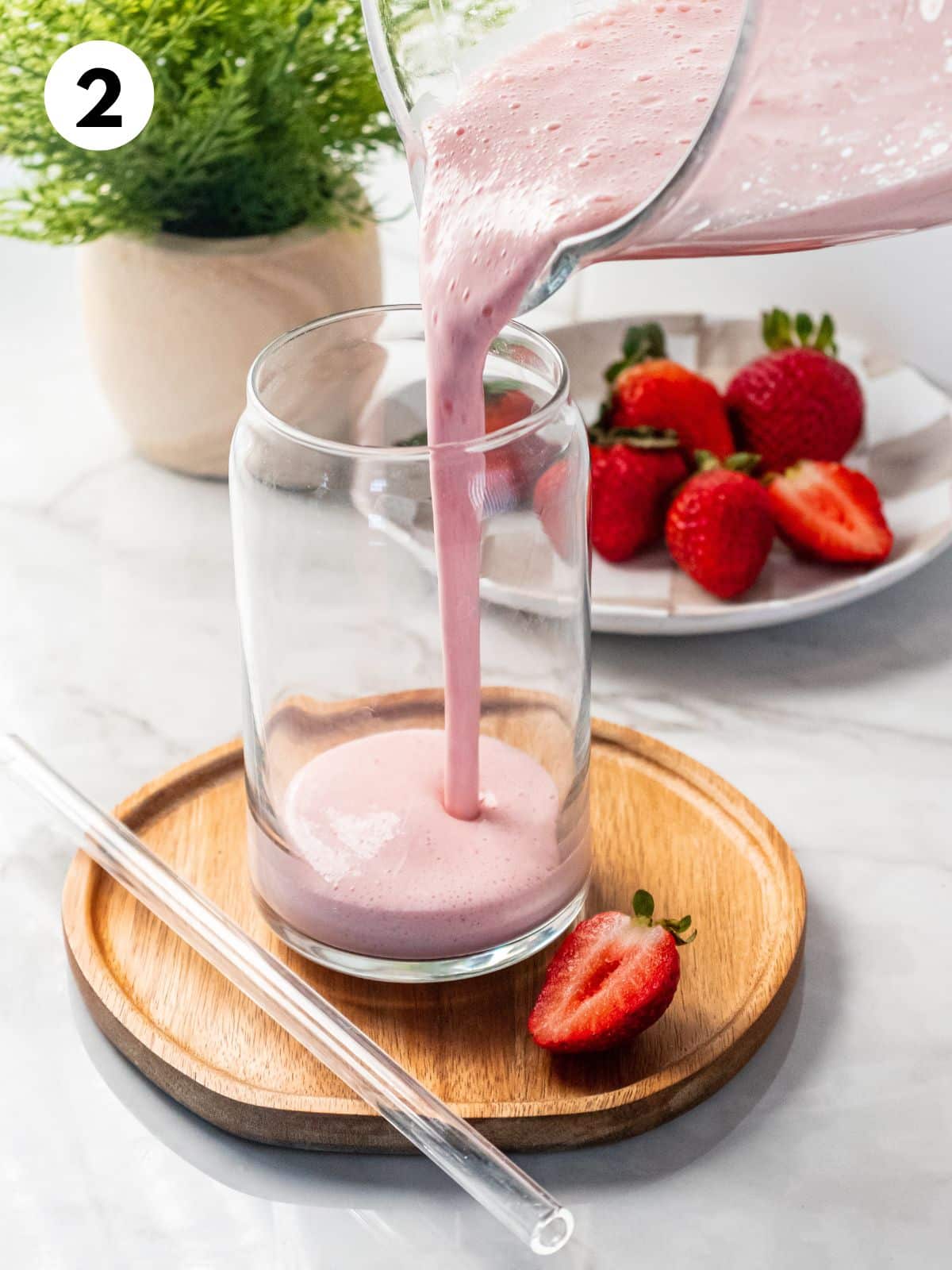 Pouring a strawberry smoothie into a glass.