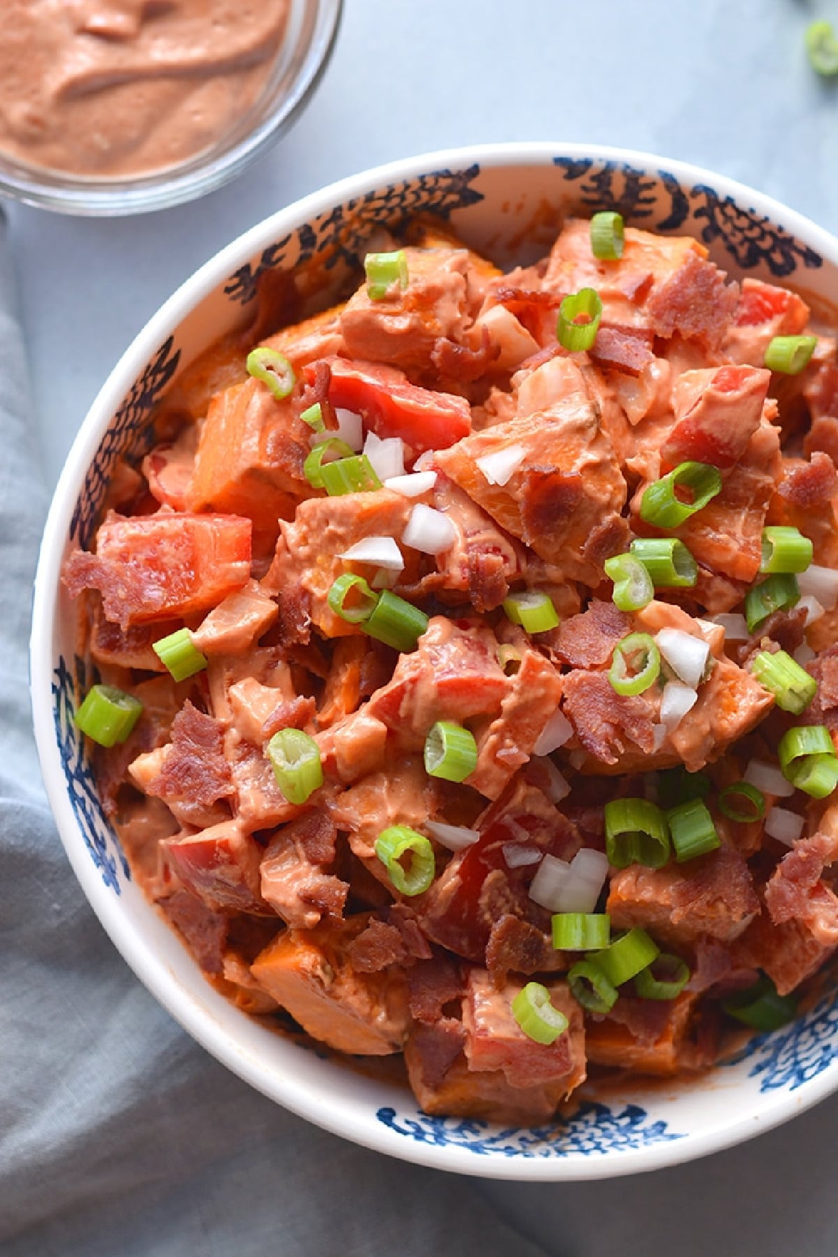 cooked yams with bacon salad in a white bowl.