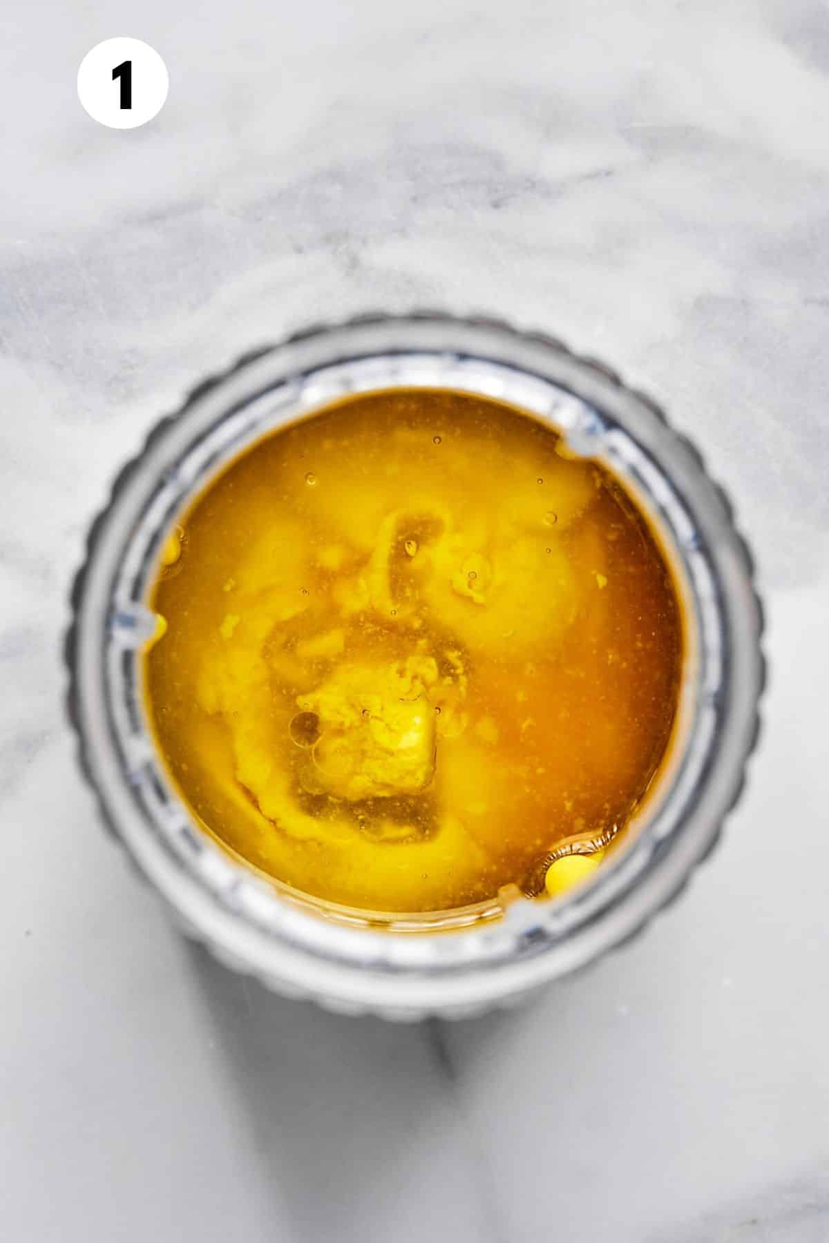 Ingredients to make the honey mustard dressing in a container. 