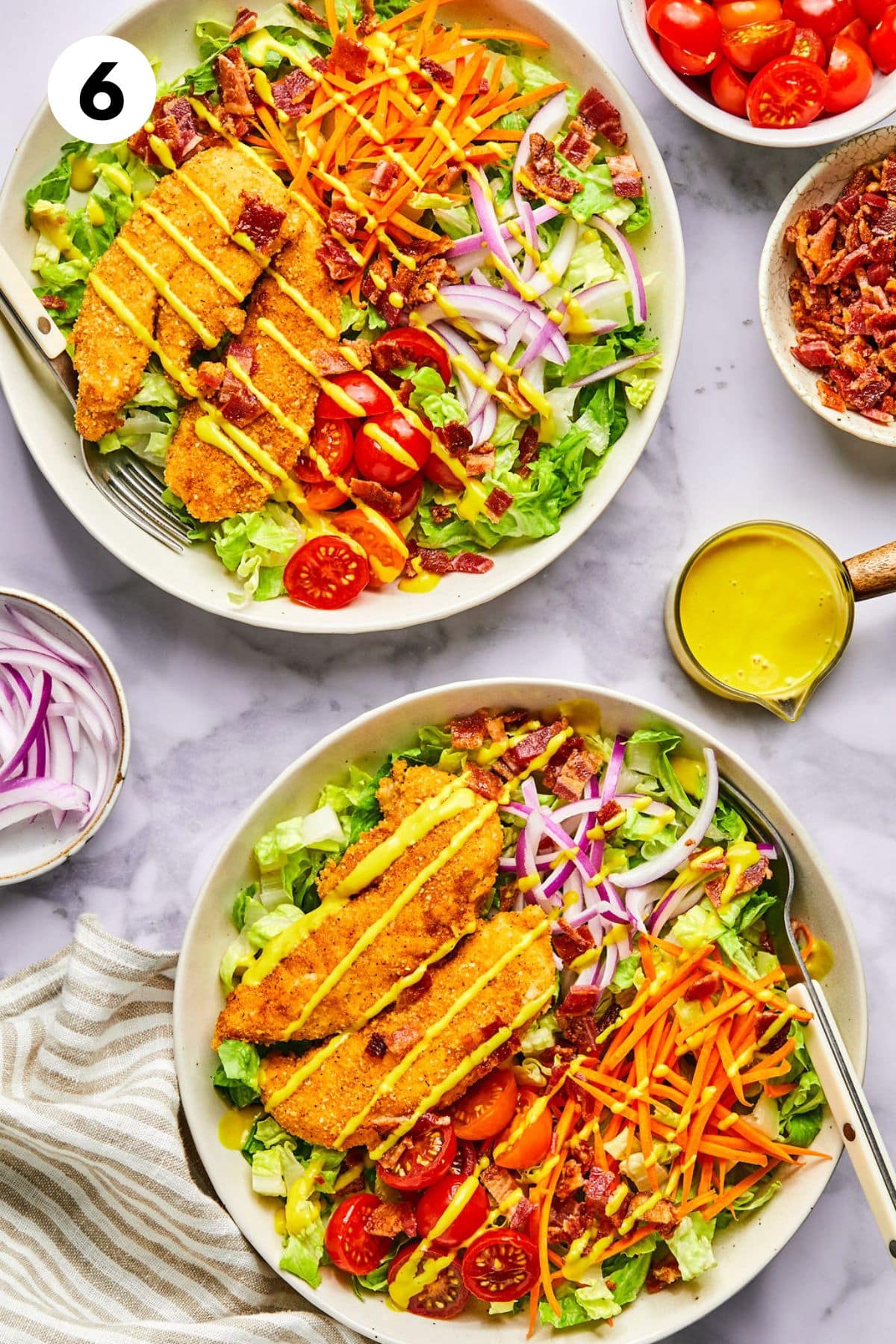 Chicken tender salads assembled in two bowls on a table. 