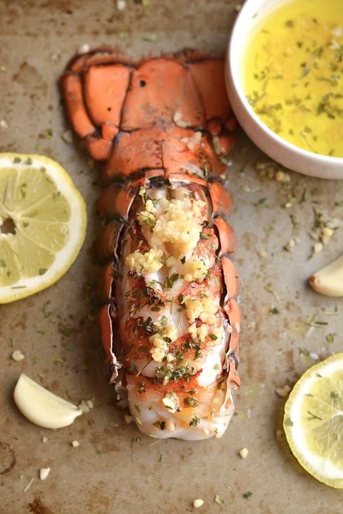 Herby Lemon Garlic Lobster never tasted this good! Baked in the oven with a lighter herby lemon garlic sauce, this simple recipe is one you'll want to make again and again. Perfect easy meal for date night! Whole30 + Paleo + Gluten Free + Low Calorie + Low Carb