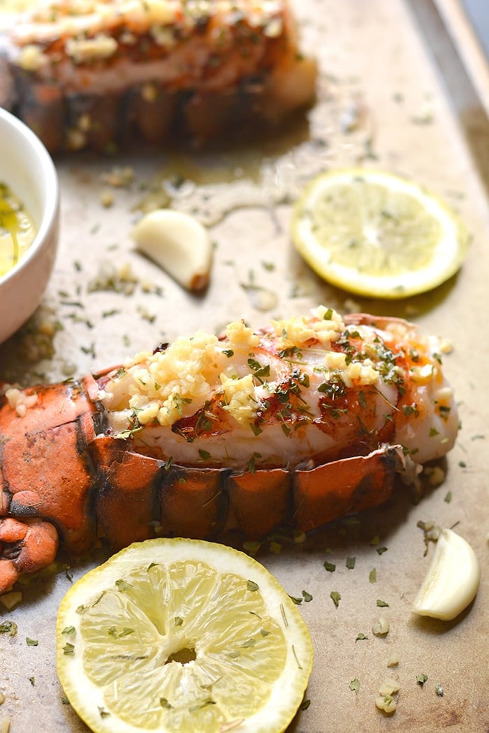 Herby Lemon Garlic Lobster never tasted this good! Baked in the oven with a lighter herby lemon garlic sauce, this simple recipe is one you'll want to make again and again. Perfect easy meal for date night! Whole30 + Paleo + Gluten Free + Low Calorie + Low Carb