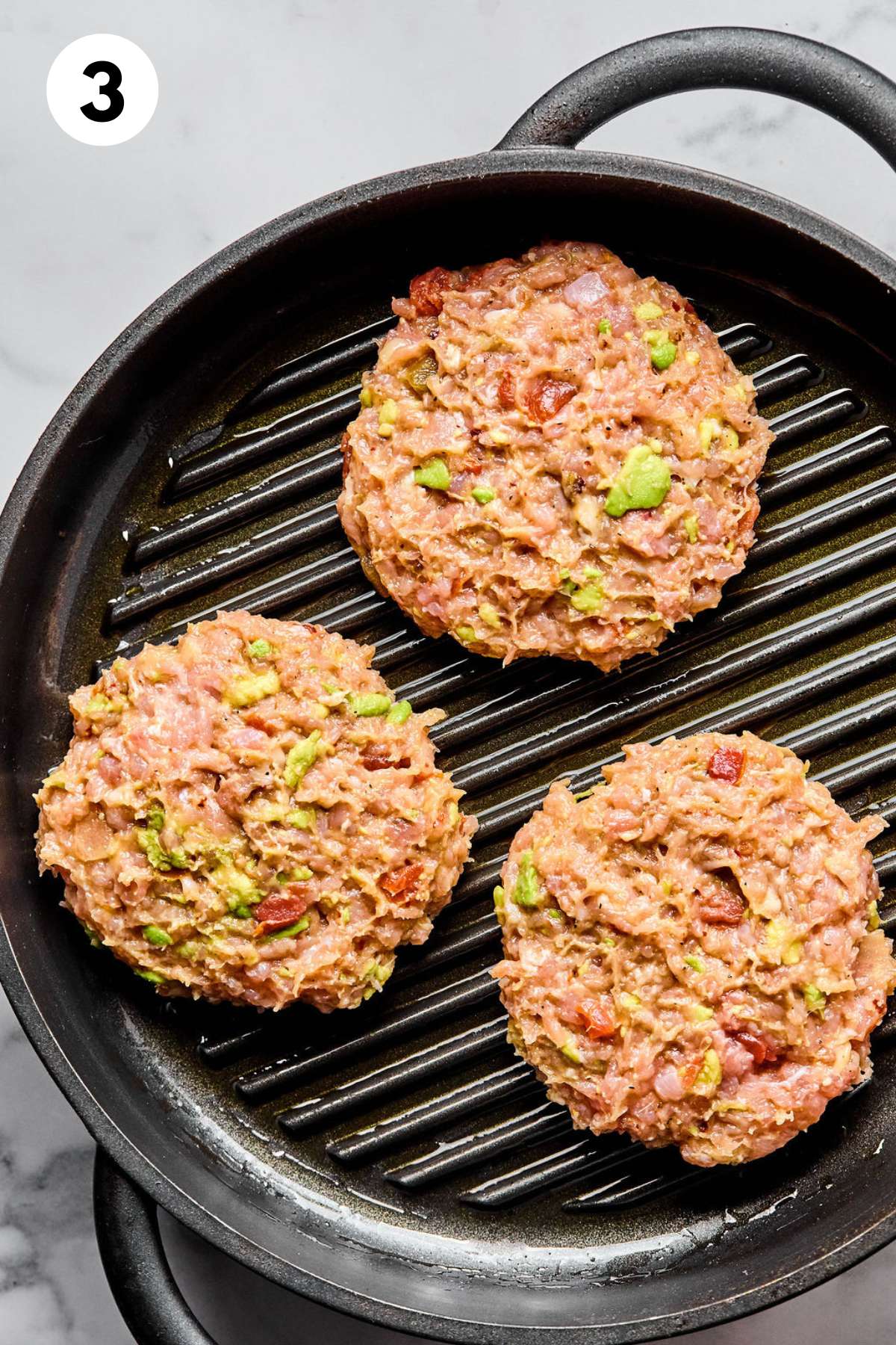 Chicken burgers added to a grill pan.