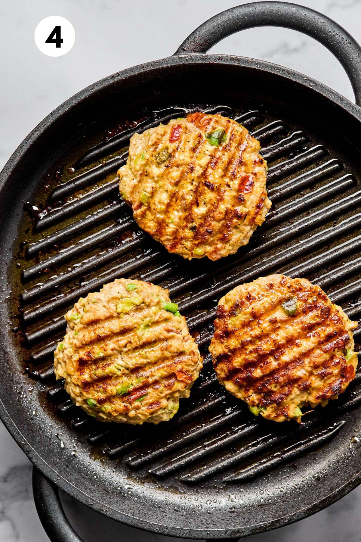 Cooked chicken burgers in a grill pan.