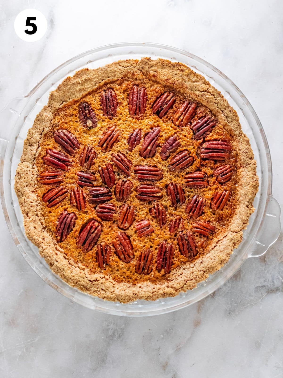 Baked healthy pecan pie in a glass pie plate.